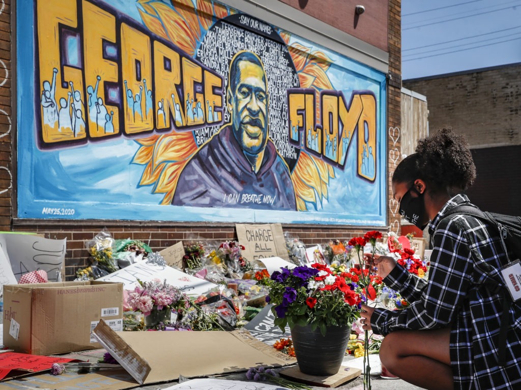 Malaysia Hammond places flowers at a memorial mural for George Floyd in Minneapolis on Sunday. Police brutality has sparked days of civil unrest. But the sparks have landed in a tinderbox built over decades of economic inequality, now exacerbated by the coronavirus pandemic.