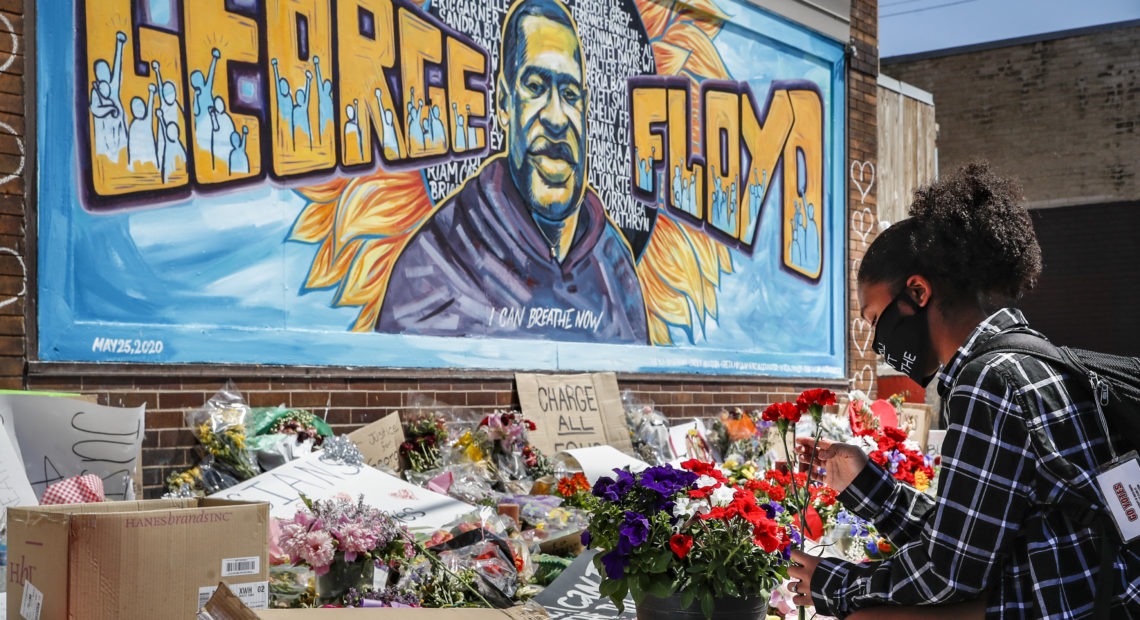 Malaysia Hammond places flowers at a memorial mural for George Floyd in Minneapolis on Sunday. Police brutality has sparked days of civil unrest. But the sparks have landed in a tinderbox built over decades of economic inequality, now exacerbated by the coronavirus pandemic.