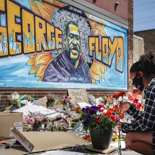 Malaysia Hammond places flowers at a memorial mural for George Floyd in Minneapolis on Sunday. Police brutality has sparked days of civil unrest. But the sparks have landed in a tinderbox built over decades of economic inequality, now exacerbated by the coronavirus pandemic.