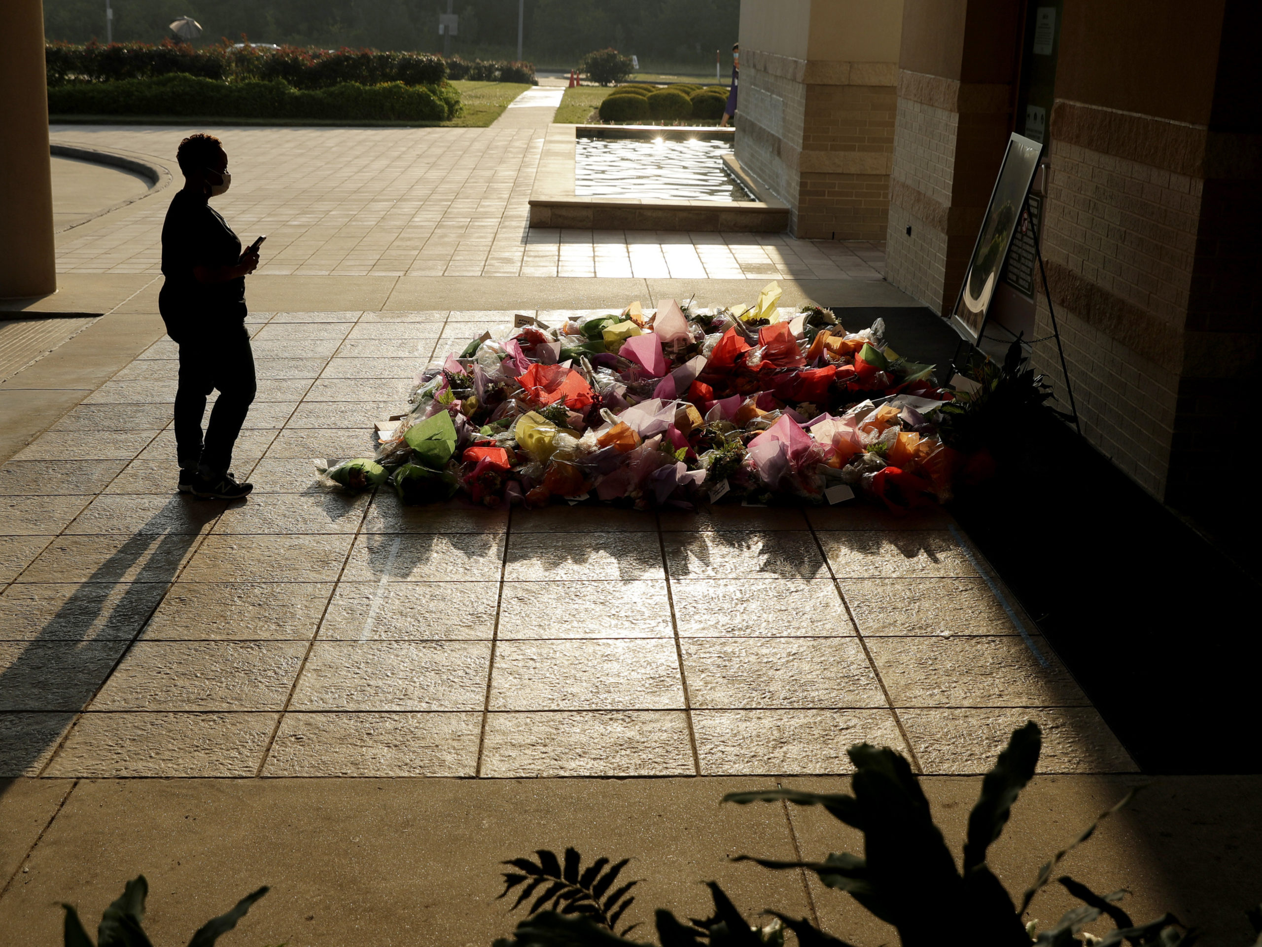 A woman stops to photograph a memorial Tuesday for Floyd at The Fountain of Praise church in Houston. CREDIT: Eric Gay/AP