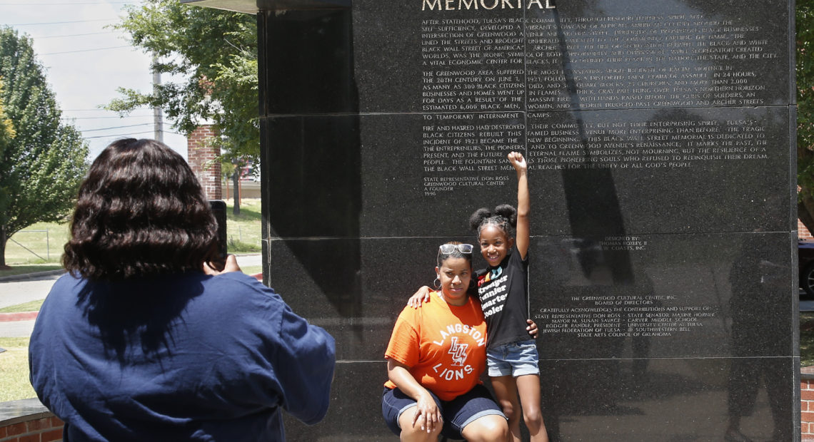 Katrina Cotton, center, of Houston poses for a photo Monday with her daughter, Kennedy Cotton, 7, at the Black Wall Street Memorial in Tulsa, Okla. CREDIT: Sue Ogrocki/AP