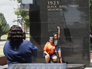 Katrina Cotton, center, of Houston poses for a photo Monday with her daughter, Kennedy Cotton, 7, at the Black Wall Street Memorial in Tulsa, Okla. CREDIT: Sue Ogrocki/AP