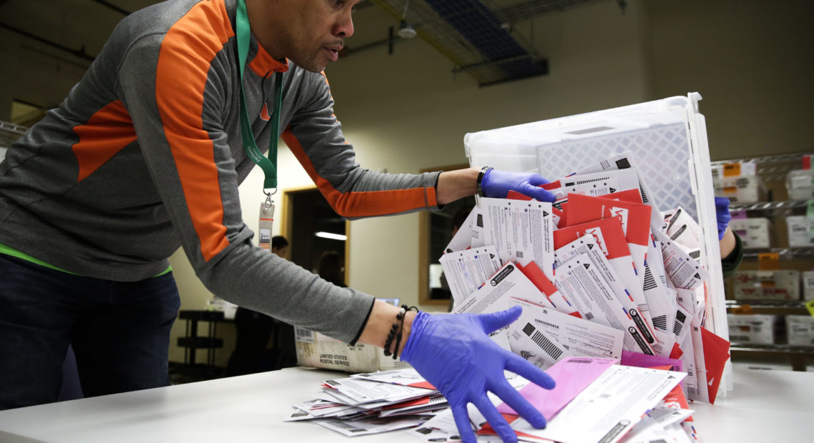 An election worker in Renton, Wash., begins processing mail-in ballots during that state's presidential primary in March. Varying state-by-state requirements around signatures and other rules have become the focus of legal fights as absentee voting expands due to the pandemic