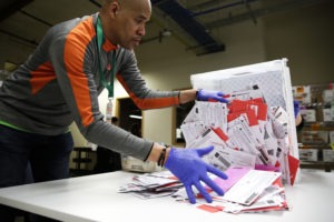 An election worker in Renton, Wash., begins processing mail-in ballots during that state's presidential primary in March. Varying state-by-state requirements around signatures and other rules have become the focus of legal fights as absentee voting expands due to the pandemic