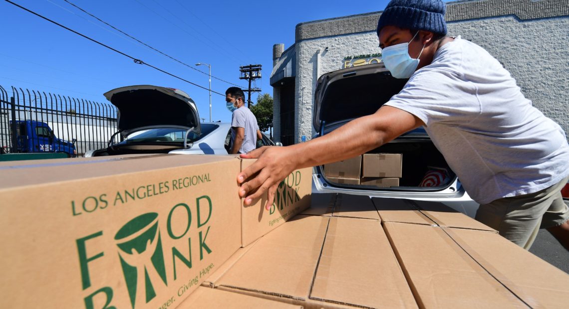 Boxes of food are loaded on vehicles last month at the Los Angeles Regional Food Bank. The country has officially entered a recession amid the pandemic, the National Bureau of Economic Research said Monday. CREDIT: Frederic J. Brown/AFP via Getty Images