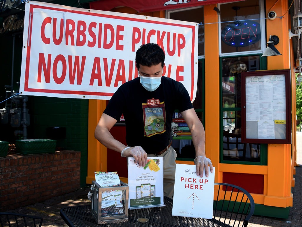 An employee sets a table for pickup orders at a restaurant in Arlington, Va. Even as states are moving to reopen their economies, tens of millions are out of work. CREDIT: Olivier Douliery/AFP via Getty Images