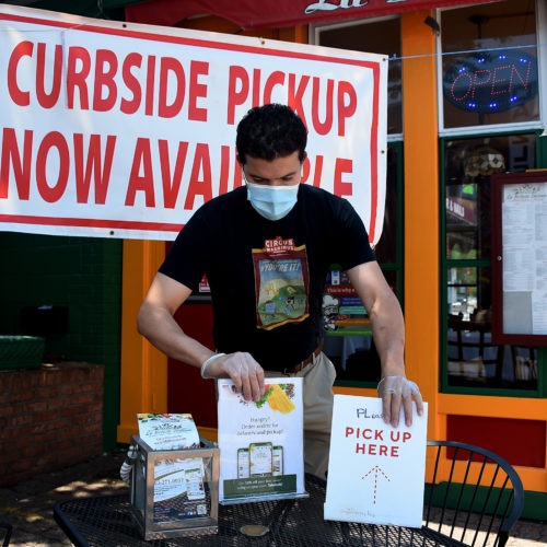 An employee sets a table for pickup orders at a restaurant in Arlington, Va. Even as states are moving to reopen their economies, tens of millions are out of work. CREDIT: Olivier Douliery/AFP via Getty Images