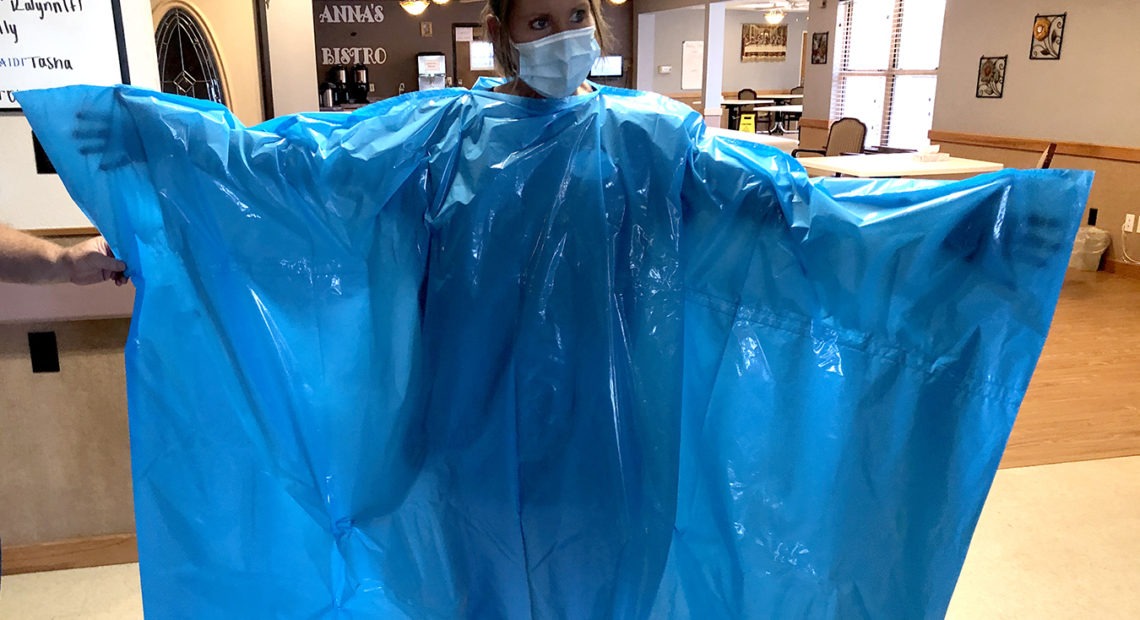 Kelly Womochil, an aide at Enterprise Estates Nursing Center in Enterprise, Kan., tries on a poncho that the Federal Emergency Management Agency is sending to nursing homes to protect against the coronavirus. CREDIT: Pamela Black