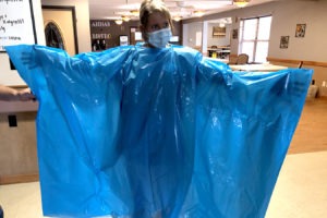 Kelly Womochil, an aide at Enterprise Estates Nursing Center in Enterprise, Kan., tries on a poncho that the Federal Emergency Management Agency is sending to nursing homes to protect against the coronavirus. CREDIT: Pamela Black