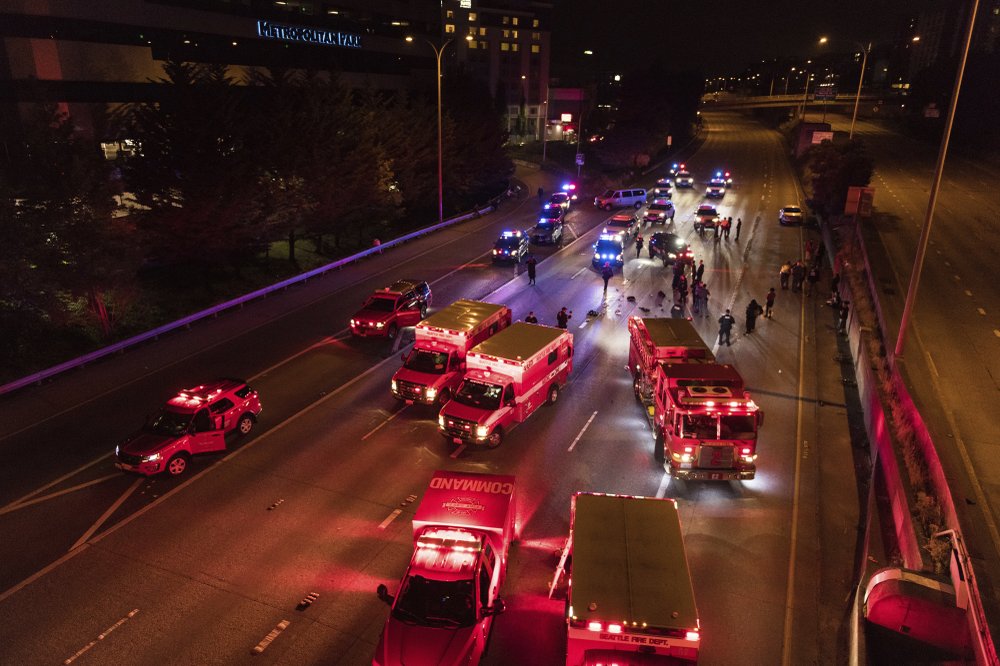 Emergency personnel work at the site where a driver sped through a protest-related closure on the Interstate 5 freeway in Seattle, authorities said early Saturday, July 4, 2020. Dawit Kelete, 27, has been arrested and booked on two counts of vehicular assault. CREDIT: James Anderson via AP