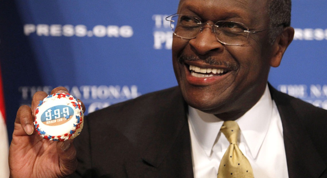 Herman Cain, then a GOP presidential candidate, holds a muffin bearing his catchphrase "9-9-9" tax plan at the National Press Club in Washington in 2011. Cain's death was announced Thursday. CREDIT: Pablo Martinez Monsivais/AP