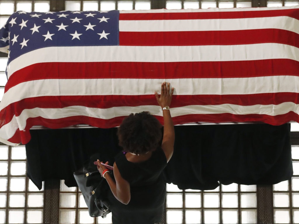 A mourner pauses by the casket of Rep. John Lewis lying in repose at the Georgia state Capitol on Wednesday in Atlanta. Lewis, who carried the struggle against racial discrimination from Southern battlegrounds of the 1960s to the halls of Congress, died on July 17. CREDIT: John Bazemore/AP