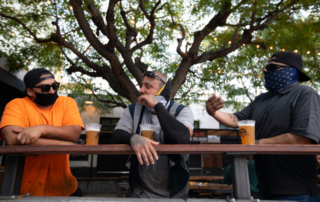 With new coronavirus infections climbing in most states, infectious disease experts are discouraging group get-togethers, especially those that involve drinking. In this photo patrons enjoy a beer outside the Central Market in Los Angeles, this week. CREDIT: Francine Orr/Los Angeles Times via Getty Images
