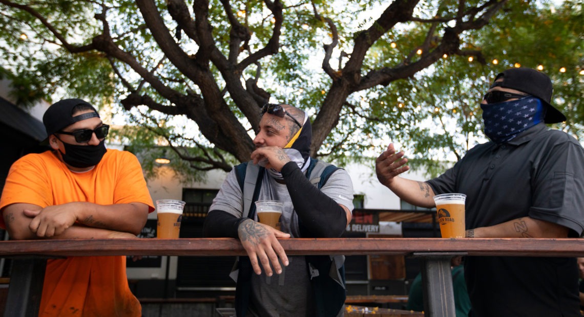 With new coronavirus infections climbing in most states, infectious disease experts are discouraging group get-togethers, especially those that involve drinking. In this photo patrons enjoy a beer outside the Central Market in Los Angeles, this week. CREDIT: Francine Orr/Los Angeles Times via Getty Images