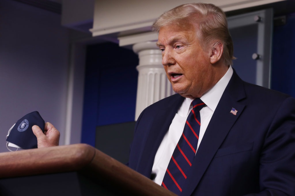 President Donald Trump holds up his face mask during a press conference at the White House on Tuesday. Chip Somodevilla/Getty Images