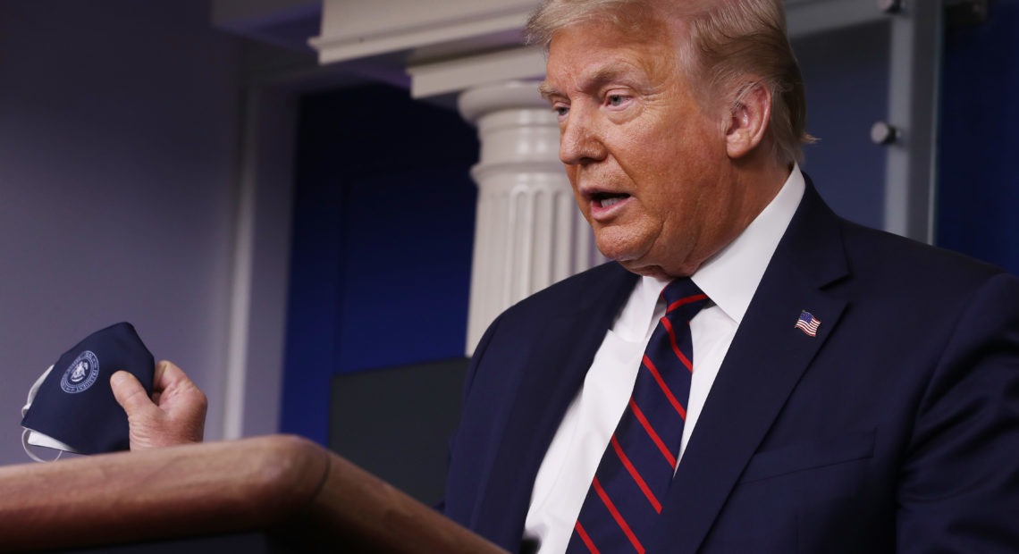 President Donald Trump holds up his face mask during a press conference at the White House on Tuesday. Chip Somodevilla/Getty Images