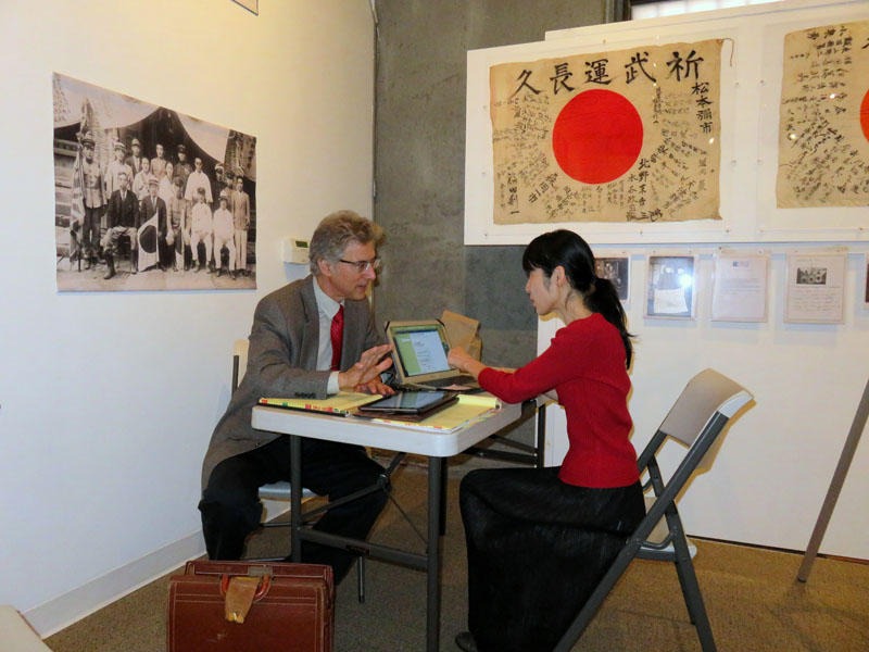 Obon Society co-founders Rex and Keiko Ziak working remotely during a temporary exhibit of yosegaki hinomaru flags in Portland in 2015. CREDIT: Tom Banse/N3