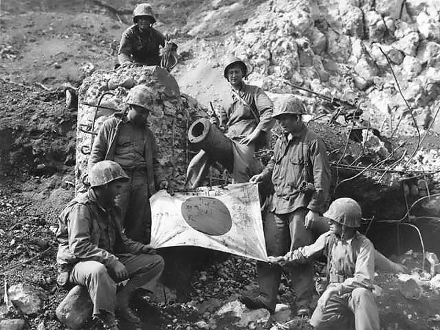 U.S. Marines posed with a captured Japanese flag on Iwo Jima. CREDIT: National Archives, USMC #112350