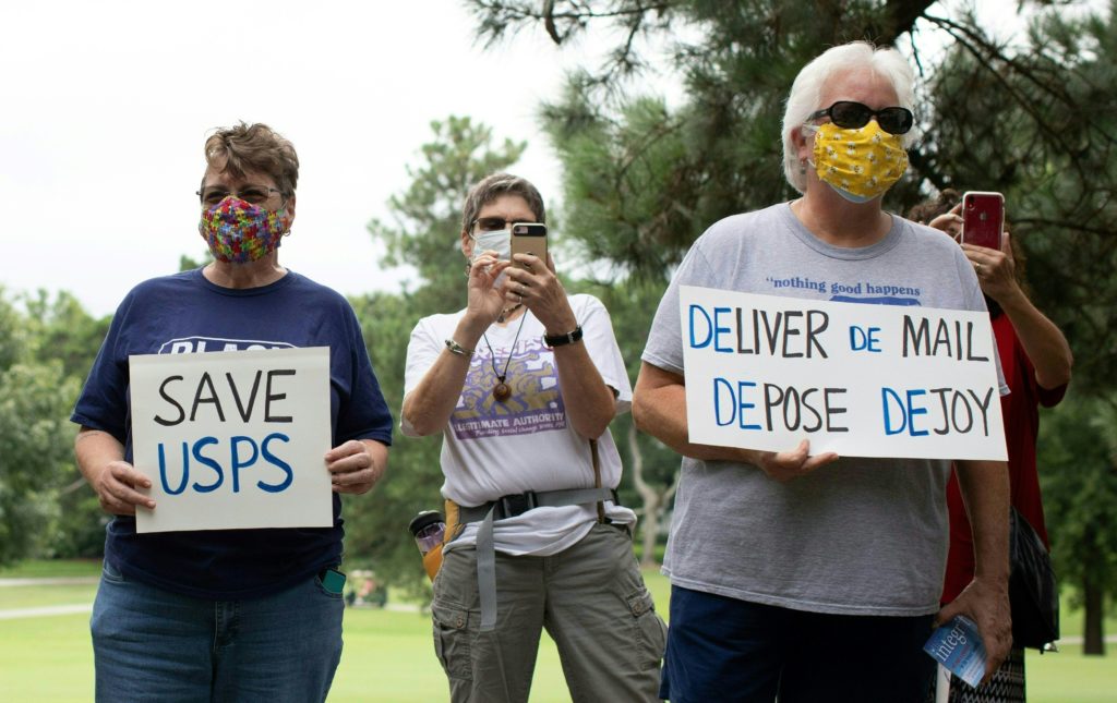 A group of protesters demonstrate in front of Postmaster General Louis DeJoy's home in Greensboro, N.C., on Sunday. Logan Cyrus/AFP via Getty Images