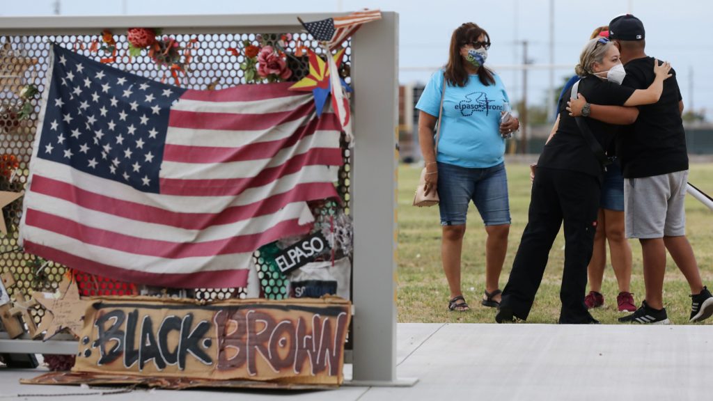 People embrace at a temporary memorial honoring victims of the Walmart shooting which left 23 people dead in a racist attack targeting Latinos on August 2, 2020 in El Paso, Texas. CREDIT: Mario Tama/Getty Images