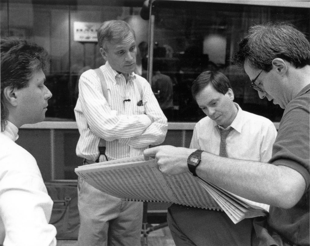 Composer Alan Menken (far left) and lyricist Howard Ashman (center-left) review a score with producer Don Hahn (far right). Walt Disney Archive