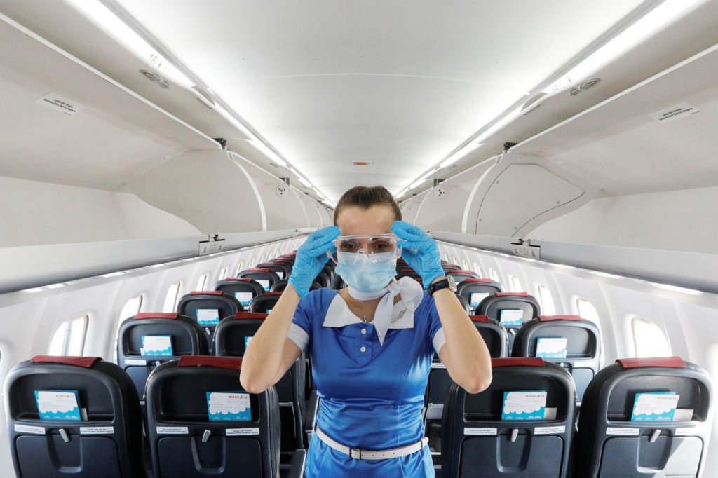 A flight attendant adjusts protective glasses. There has been little documentation about COVID-19 transmission on planes. CREDIT: Valentyn Ogirenko/Reuters