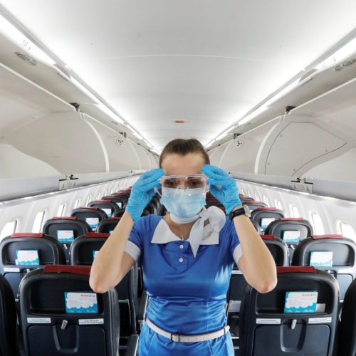 A flight attendant adjusts protective glasses. There has been little documentation about COVID-19 transmission on planes. CREDIT: Valentyn Ogirenko/Reuters
