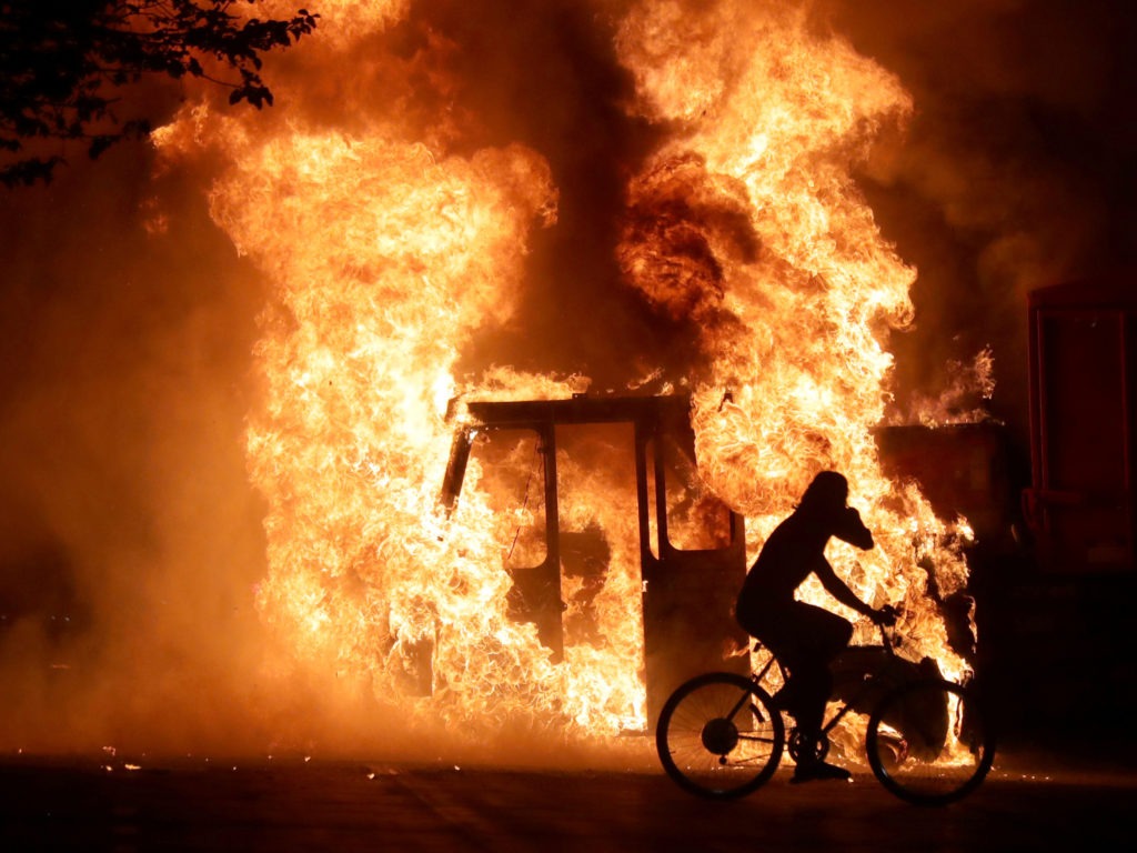 A person on a bike rides past a city truck on fire outside the Kenosha County Courthouse in Kenosha, Wis., during protests following the police shooting of Black man Jacob Blake on Sunday. Mike De Sisti/Milwaukee Journal Sentinel via USA Today/Via Reuters