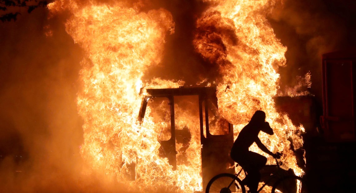 A person on a bike rides past a city truck on fire outside the Kenosha County Courthouse in Kenosha, Wis., during protests following the police shooting of Black man Jacob Blake on Sunday. Mike De Sisti/Milwaukee Journal Sentinel via USA Today/Via Reuters