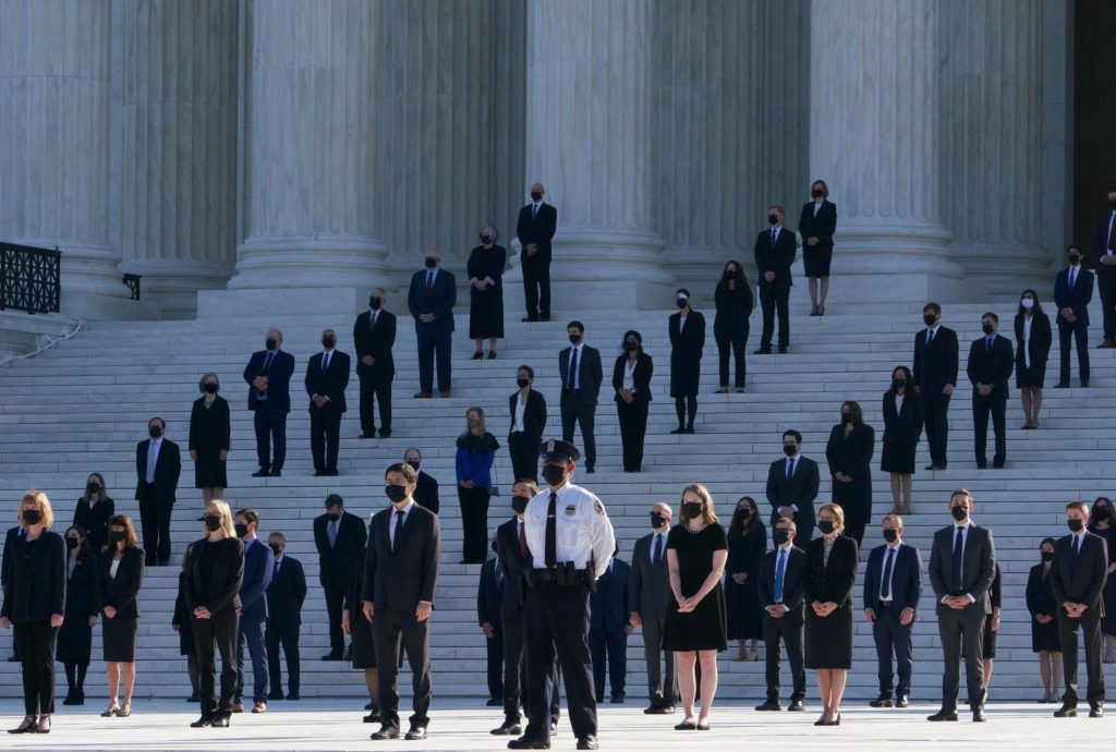 Former law clerks for Justice Ruth Bader Ginsburg stand on the steps of the U.S. Supreme Court in Washington, D.C., as they await the arrival of the casket on Wednesday. CREDIT: Claire Harbage/NPR