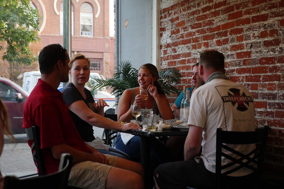 The Ehrman, Hammond and Ring families enjoy wine at The Red Pickle restaurant in Ellensburg on Sept. 9, 2020, while their children play at other tables. The families come two times a week, owner Mario Alfaro said, and are just a handful of the many regular customers he's come to know by name. CREDIT: Emily McCarty/Crosscut