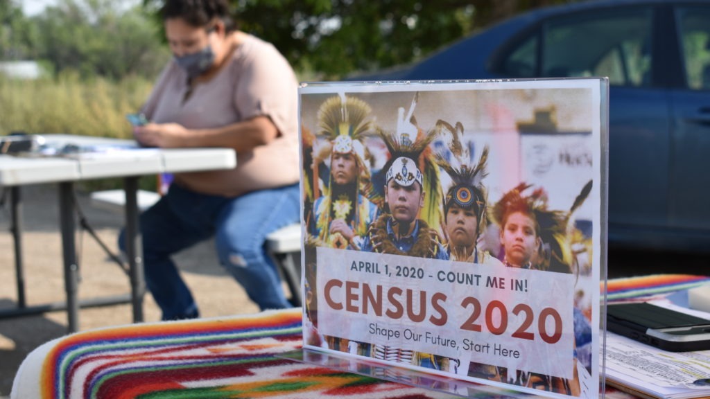 A sign promoting participation in the 2020 census is displayed as Selena Rides Horse enters information into a phone for a member of the Crow Indian Tribe in Lodge Grass, Mont., in August. Matthew Brown/AP