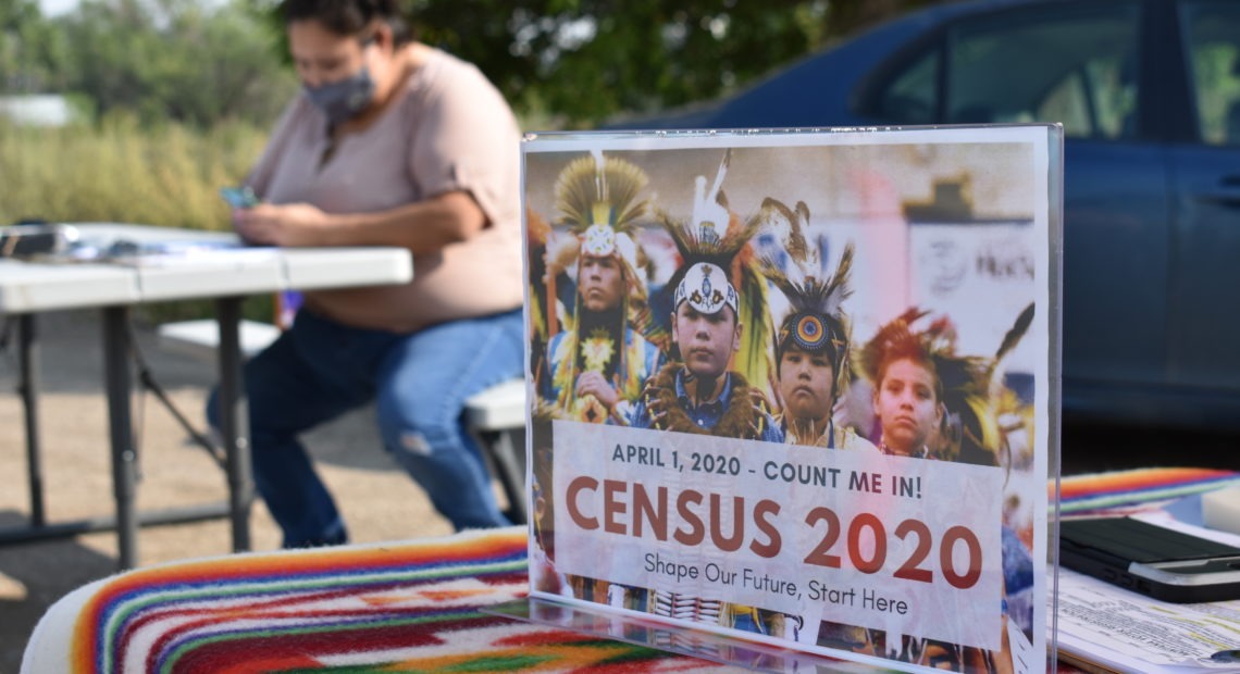 A sign promoting participation in the 2020 census is displayed as Selena Rides Horse enters information into a phone for a member of the Crow Indian Tribe in Lodge Grass, Mont., in August. Matthew Brown/AP