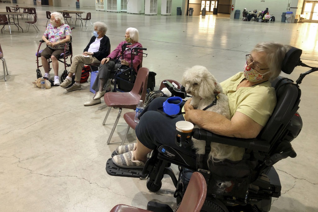 Patricia Fouts sits with her dog, Murphy, and other evacuated residents of a senior living home in an evacuation center at the Oregon State Fairgrounds in Salem, Ore., on Tuesday. Marian Estates senior living home in Sublimity, Ore., was evacuated early Tuesday as a wildfire closed in on the area. CREDIT: Andrew Selsky/AP