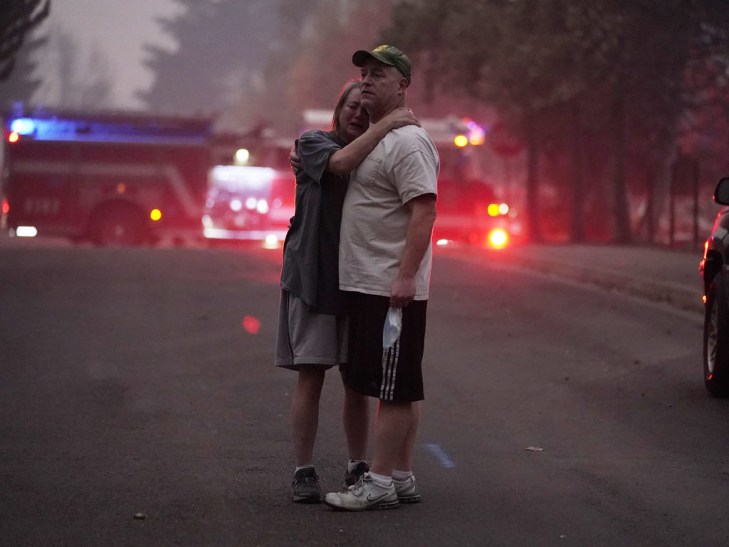 A couple embrace Thursday, Sept. 10, 2020, while touring an area devastated by the Almeda Fire in Phoenix, Ore. John Locher/AP