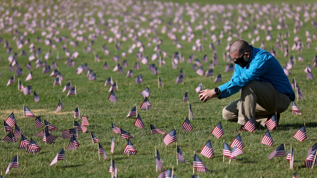 The U.S. hit a tragic milestone Tuesday, recording more than 200,000 coronavirus deaths. Here, Chris Duncan, whose mother, Constance, 75, died from COVID-19 on her birthday, visits a COVID Memorial Project installation of 20,000 American flags on the National Mall. The flags are on the grounds of the Washington Monument, facing the White House. Win McNamee/Getty Images