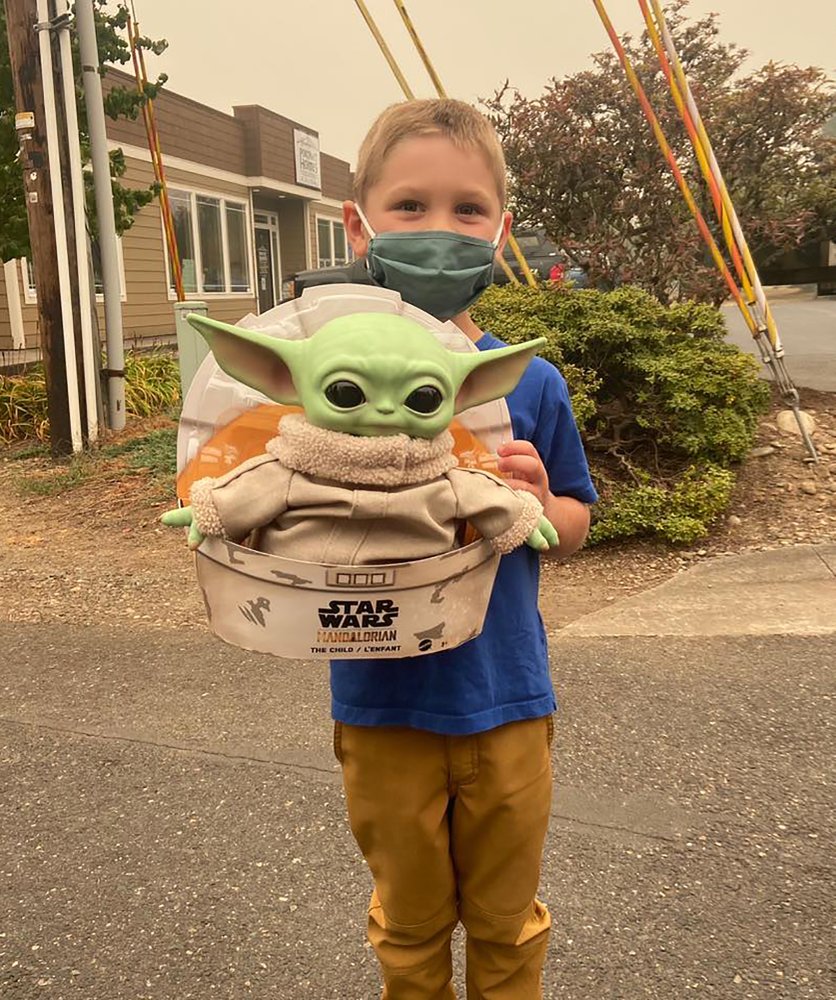 Five-year-old Carver holds up a Baby Yoda toy on Saturday, Sept. 12, 2020 in Scappoose, Oregon. Carver donated the toy to Oregon firefighters, who have been having fun posing the tiny green Force user on the fire lines since. Carver and his grandmother delivered a toy version of the character from "The Madalorian" series to a donation center for firefighters along with a note that read, “Here is a friend for you in case you get lonely.” Courtesy of Tyler Eubanks via AP