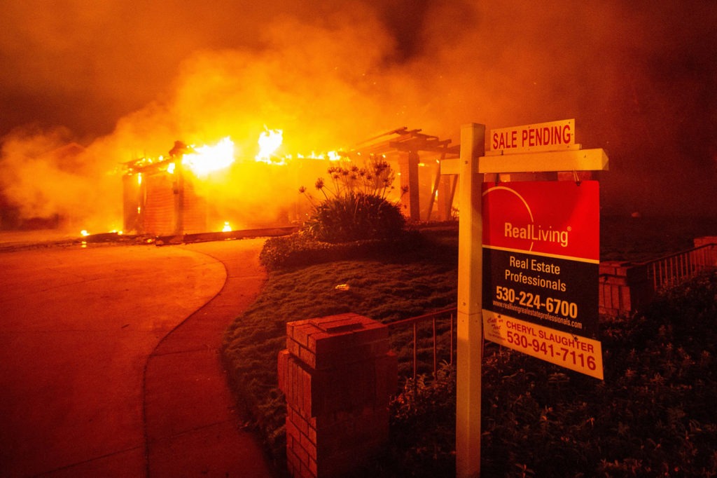 A real estate sign is seen in front of a burning home during the Carr Fire in Redding, Calif., in 2018. More than 1,600 buildings reportedly were destroyed. Josh Edelson/AFP via Getty Images