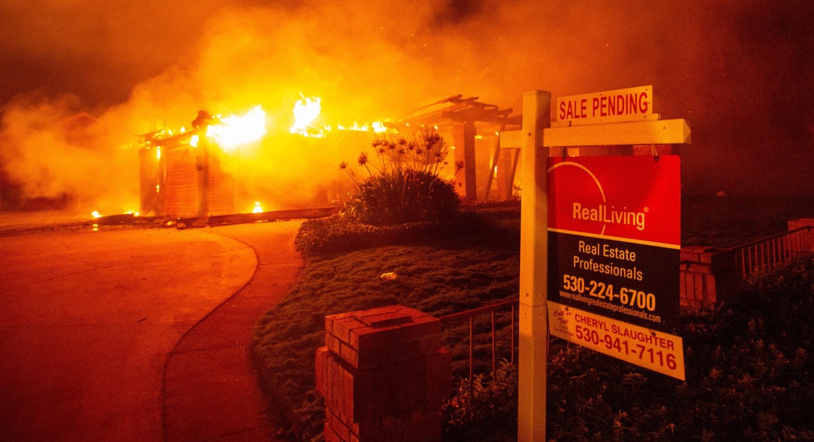 A real estate sign is seen in front of a burning home during the Carr Fire in Redding, Calif., in 2018. More than 1,600 buildings reportedly were destroyed. Josh Edelson/AFP via Getty Images