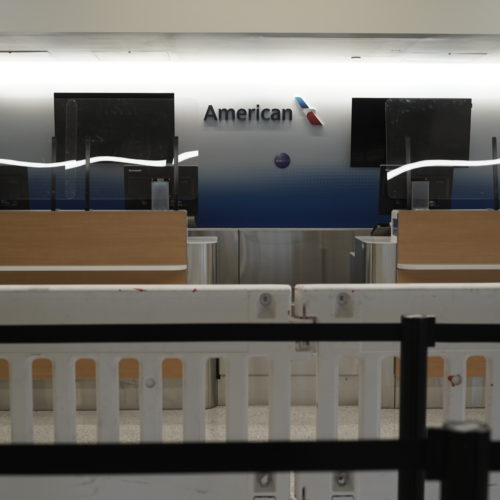 American Airlines check-in counters sit closed last month behind plastic barriers at Los Angeles International Airport. CREDIT: Bing Guan/Bloomberg via Getty Images