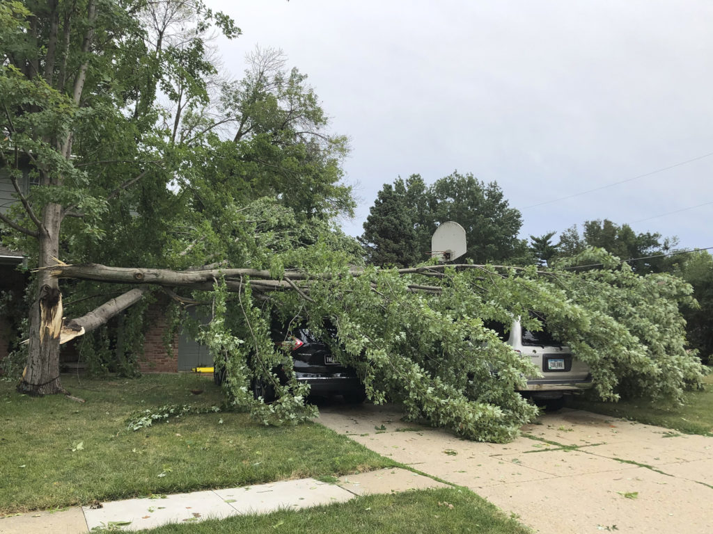 A tree fell across vehicles at a home in West Des Moines after a severe thunderstorm moved across Iowa on Aug. 10. It was the costliest storm system in modern U.S. history. CREDIT: David Pitt/AP