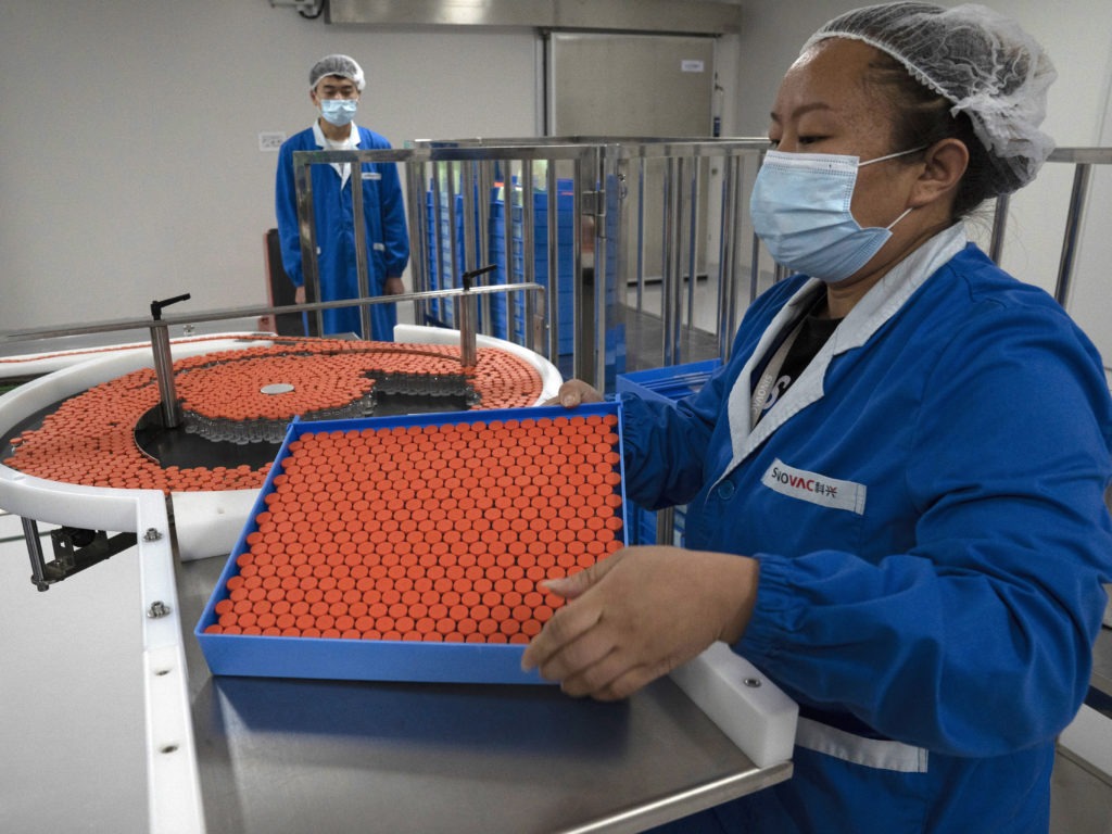 A worker feeds vials for production of a vaccine for COVID-19 at the SinoVac vaccine factory in Beijing. China said on Friday that it is joining the COVID-19 vaccine alliance known as COVAX. Ng Han Guan/AP