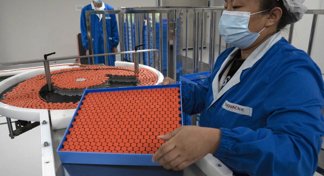 A worker feeds vials for production of a vaccine for COVID-19 at the SinoVac vaccine factory in Beijing. China said on Friday that it is joining the COVID-19 vaccine alliance known as COVAX. Ng Han Guan/AP