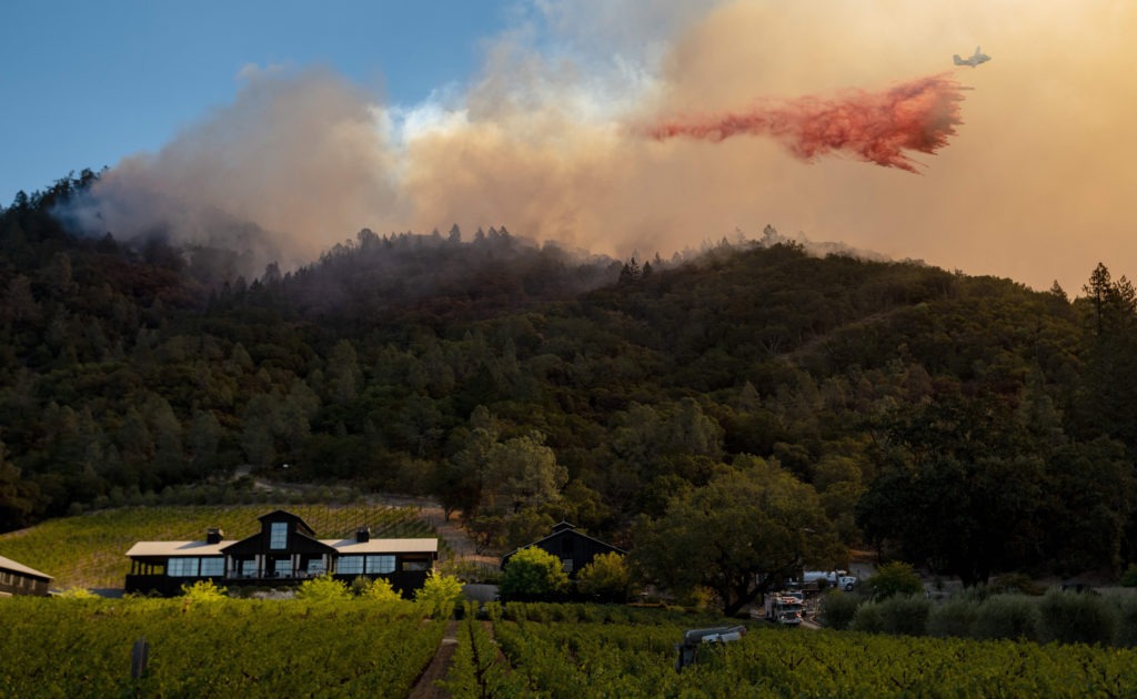 A California Department of Forestry and Fire Protection airplane drops fire retardant along a burning hill during the Glass Fire in Calistoga, Calif., in September. California is one of two states to require wildfire risk be disclosed to new homebuyers. CREDIT: Josh Edelson/AFP via Getty Images