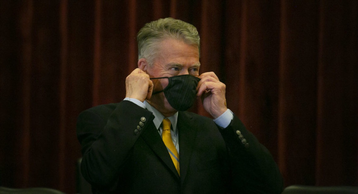 File photo. Idaho Gov. Brad Little puts on a face mask before a public meeting earlier this year. So far he has resisted calls for a statewide mandate. On Sunday, Nov. 8, the governor of Utah, Idaho's southern neighbor, imposed a mask mandate. CREDIT: Idaho Education News