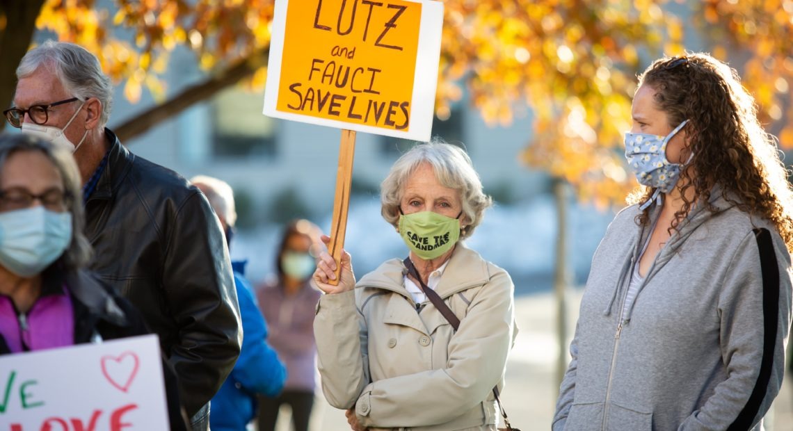 Carolyn Holmes holds a sign in favor of Dr. Anthony Fauci and Health Officer Bob Lutz during a protest against the Spokane Board of Health's ousting of Lutz, held on Nov. 1, 2020 outside the Spokane Regional Health District office. News of the controversial situation broke on Friday, and Lutz has since said that he will not resign and has acquired an attorney in order to keep his employment with the SRHD in the middle of the COVID-19 pandemic.