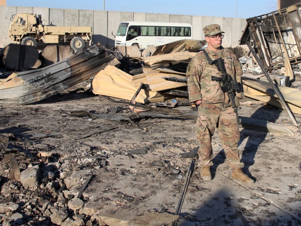 A U.S. soldier stands at a spot struck by Iranian missiles in January at Ain al-Asad air base in Iraq's Anbar province. The attack was in retaliation for the U.S. drone strike that killed Iranian Gen. Qassem Soleimani. The U.S. is drawing down 2,500 troops in Iraq and Afghanistan. Qassim Abdul-Zahra/AP