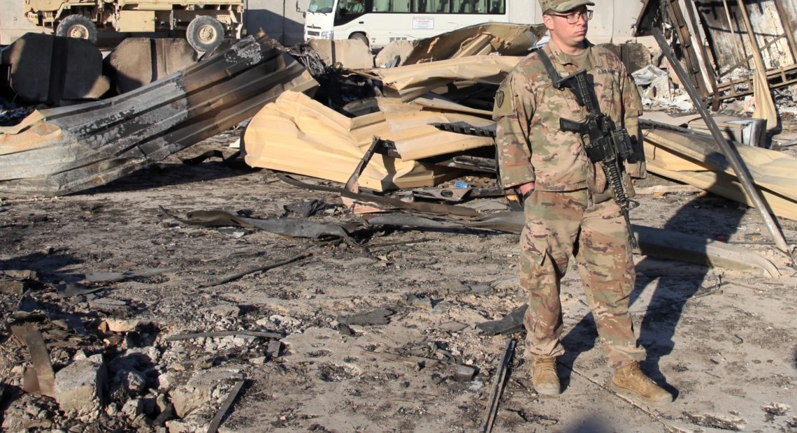 A U.S. soldier stands at a spot struck by Iranian missiles in January at Ain al-Asad air base in Iraq's Anbar province. The attack was in retaliation for the U.S. drone strike that killed Iranian Gen. Qassem Soleimani. The U.S. is drawing down 2,500 troops in Iraq and Afghanistan. Qassim Abdul-Zahra/AP