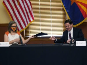 Arizona Secretary of State Katie Hobbs and Gov. Doug Ducey exchange election documents as they certify election results Monday at the Arizona Capitol in Phoenix. CREDIT: Ross D. Franklin/AP