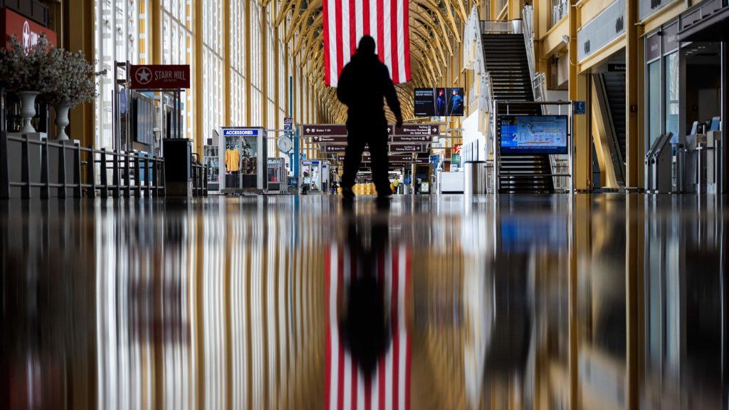 An airport employee walks through Reagan National Airport in Arlington, Va., earlier this year. On Thursday, the Centers for Disease Control and Prevention warned that Americans should refrain from traveling for the upcoming holiday. CREDIT: Andrew Caballero-Reynolds/AFP via Getty Images